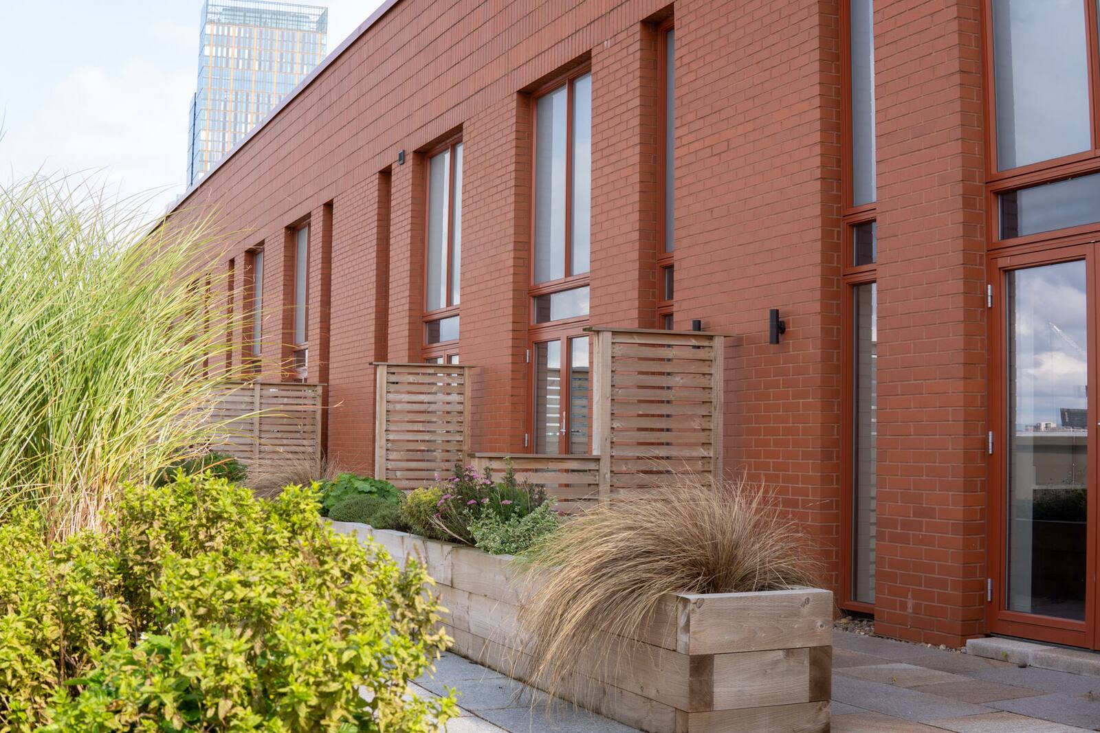 A roof terrace with timber planters at a red-brick apartment building.