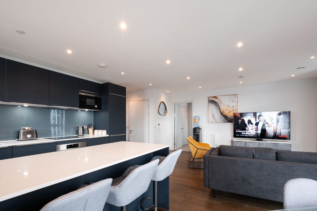 Open-plan kitchen and living space with a navy island and bar seating.