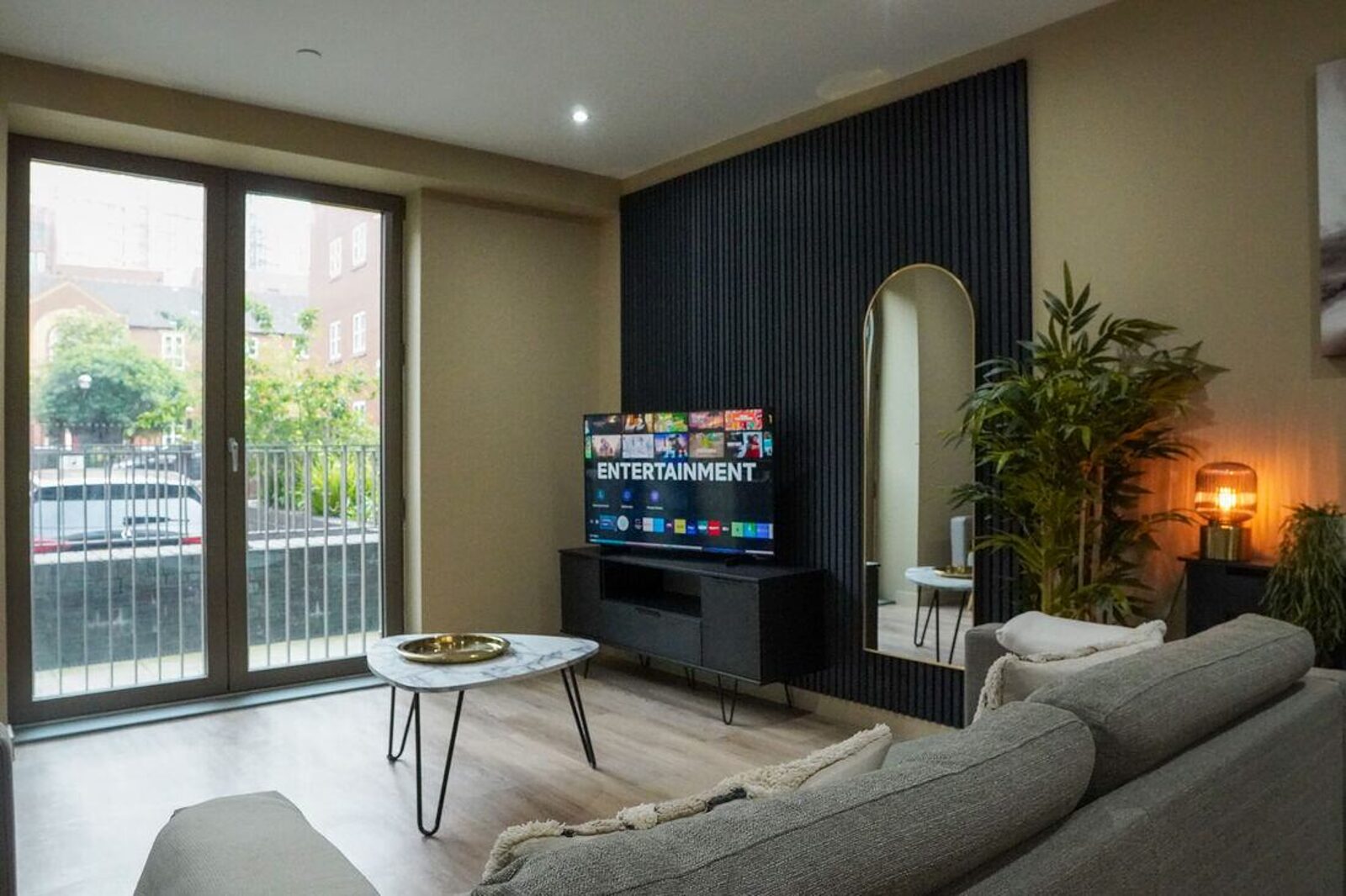 A managed apartment living room with full-height doors onto a balcony and a slatted feature wall.